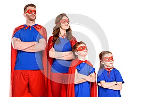 confident family of superheroes in costumes standing with crossed arms and looking away