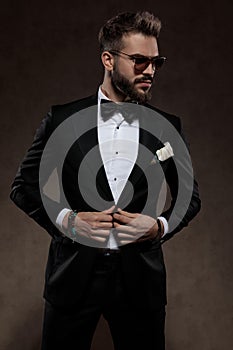 Confident fashion groom unbuttoning his jacket