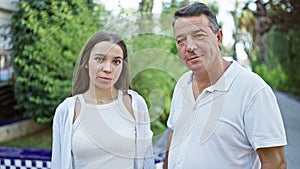 Confident father and his lovely daughter, two happy family members, standing together, enveloped in sunny park sunlight, joyfully