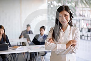 Confident female customer services agent with headset working in a call center office. Customer service team support concept