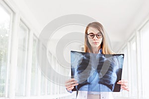 Confident female doctor examining accurately a rib cage x-ray.