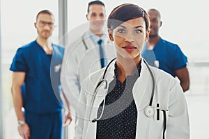 Confident female doctor in front of team