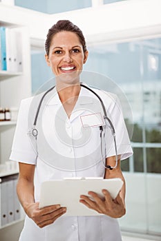 Confident female doctor holding clipboard in medical office