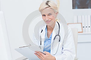 Confident female doctor holding clipboard