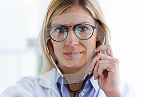 Confident female doctor looking at camera and holding the stethoscope in the consultation.