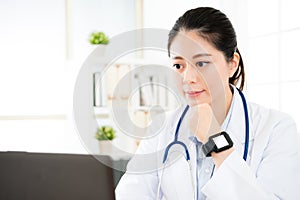Confident female doctor looking at mobile computer