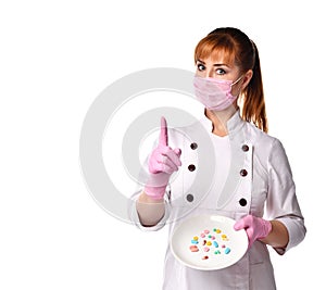 Confident lady doctor in medical mask holding plate with pills in assortment pointing index finger up. Waist-up shot isolated on