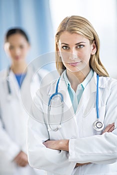 Confident Female Doctor Standing Arms Crossed In Clinic