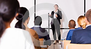 Confident female lecturer speaking to businesspeople at seminar photo