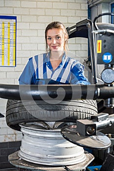 Confident Female Mechanic Mounting Car Tire On Rim In Garage