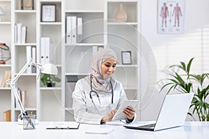 Confident female muslim doctor in hijab consulting patients in clinic office