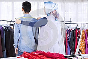 Confident female muslim fashion designer measuring clients shoulder