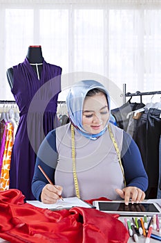 Confident female muslim fashion designer working with garments