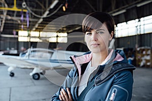 Confident female pilot posing in the hangar