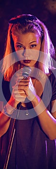 Confident female singer with drummer performing on illuminated stage in nightclub