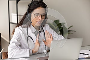 Confident female therapist in headphones consult patient by video call