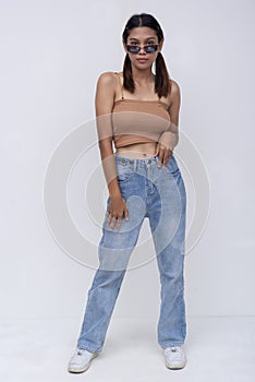 A confident Filipino woman in her late teens or early 20s. Wearing a brown top and loose fitting jeans. Isolated on a white photo