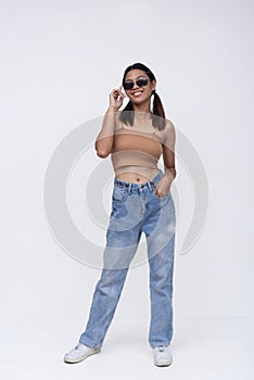 A confident Filipino woman in her late teens or early 20s. Wearing a brown top and loose fitting jeans. Isolated on a white photo