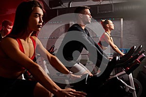 confident fit caucasian people exercising and working out in gym, cycling machine bicycle