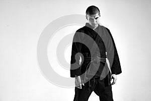 Confident frowning aggressive guy in kimono for mix fight on studio background with copy space, black and white portrait