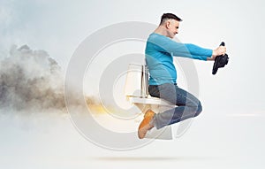 Confident funny man is flying sitting on the toilet, holding a car steering wheel, smoke exhaust from behind, on a light