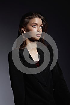 Confident gaze of a woman in a chic blazer over a burgundy top, radiating poise and modern style