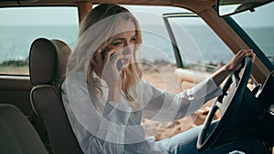 Confident girl answering call sitting retro car at sunny seashore close up.