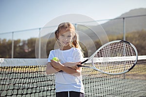 Confident girl holding tennis racket and ball at court