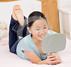 Confident girl laying on bed viewing reflection photo