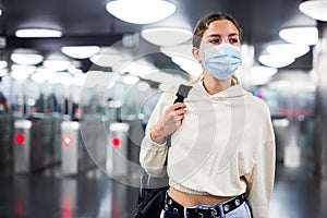 Confident girl in a protective mask entered the subway, passing through the turnstile