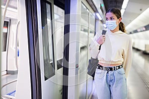 Confident girl in a protective mask in the subway is about to enter the train photo