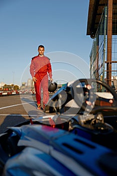 Confident go-kart driver walking to car before race at starting line