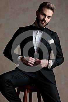 Confident groom smiling and unbuttoning his jacket