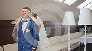 Confident groom standing in the cafe while blonde bride closes his eyes with her hands