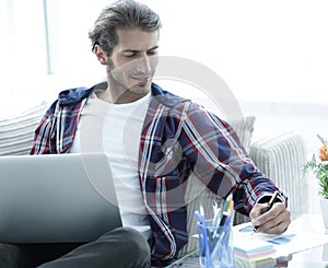 Confident guy working with laptop at home.