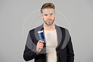 Confident in hair care product. Man stylish hairstyle holds bottle hygienic product grey background. Switch matte