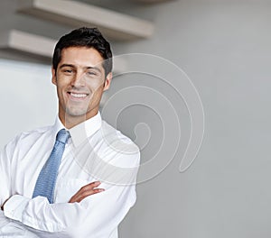 Confident and handsome executive alongside copyspace. A handsome young businessman crossing his arms and looking at you