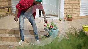 Confident handsome man standing up from porch taking gardening tools and leaving. Wide shot of young African American
