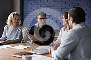 Confident handsome millennial businessman talking to colleagues