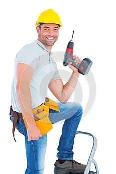 Confident handyman holding power drill while climbing ladder