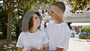 Confident, happy couple in love laughing, enjoying the green outdoors of the park, hugging, looking at each other with beautiful