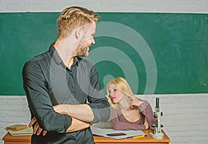 Confident in his knowledge. Handsome man standing hands crossed in classroom with teacher. Male student with examiner at