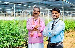 Confident indian banker or office with Indian village famer standing with arms corssed by looking at camera at green