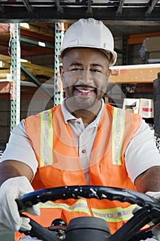 Confident Industrial Worker Driving Forklift At Workplace