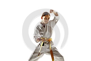 Confident junior in kimono practicing hand-to-hand combat, martial arts