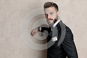 Confident leaning on wall while wearing tuxedo