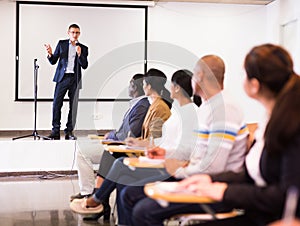 Confident lecturer speaking to businesspeople at seminar