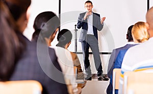 Confident lecturer speaking to businesspeople at seminar