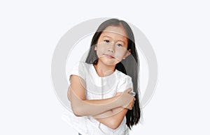 Confident little Asian child girl with expression cross one`s arm and looking camera isolated on white background. Cheerful kids