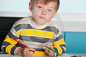 Confident little boy is sitting at the desk